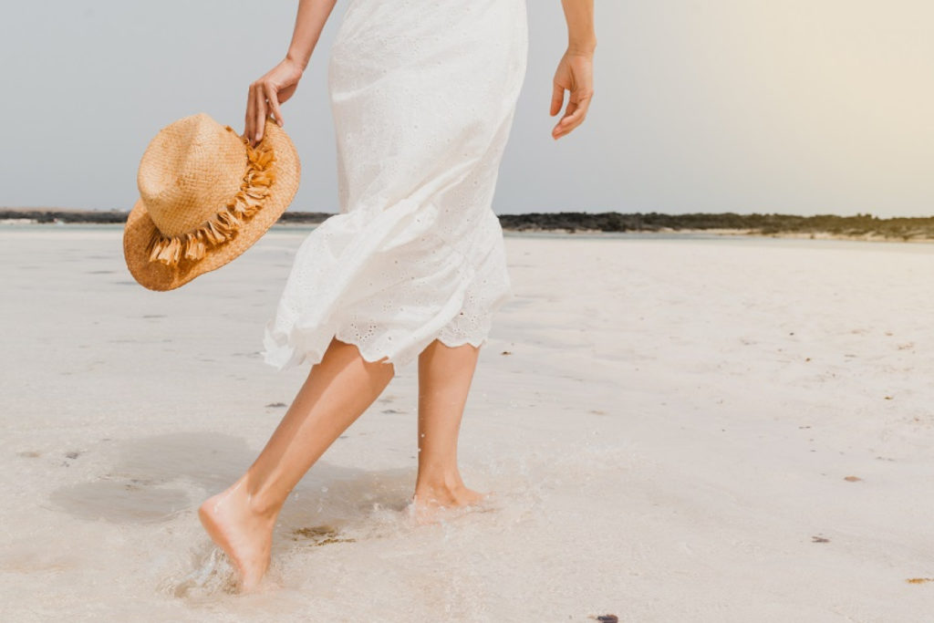 femme en robe se promenant au bord de la plage